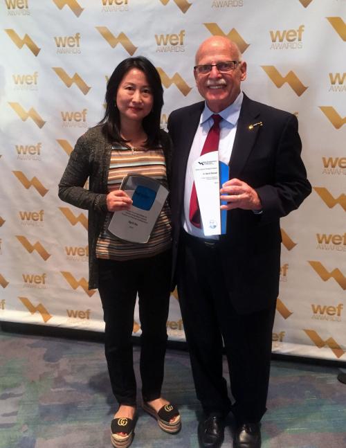 April Gu holding award with man at WEF awards