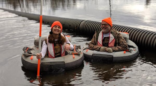 Eirini Sarri and Mike Rolband in inner tubes in a pond, smiling