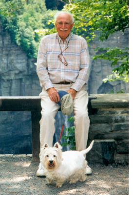 Image of Professor Walter Lynn smiling with white dog at his feet on a leash