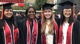 4 students with caps and gowns on at commencement