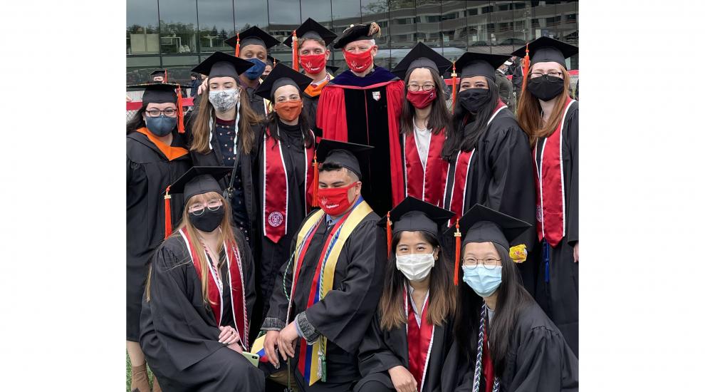 Prof. Hover with students dressed up with caps and gowns