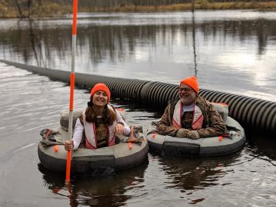 student and prof wading in pond in rafts