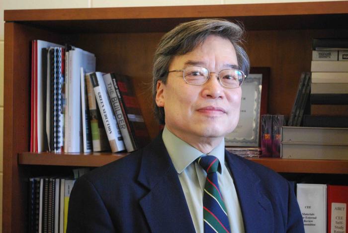 Phillip Liu in front of bookshelf.