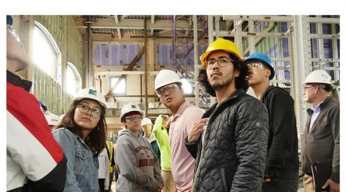 Students with hard hats at a construction site.